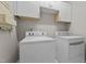 Bright laundry room with modern washer and dryer units and white cabinets at 1302 Ingle Ct, Burlington, NC 27215