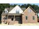 New brick home with white trim windows and a covered porch, set against a backdrop of mature trees at 1589 S Old Carriage Rd, Rocky Mount, NC 27804