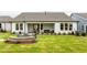 Spacious backyard with lush green grass, a cozy fire pit, and a covered patio at 1605 Garden Park Cir, Fuquay Varina, NC 27526