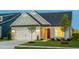 Inviting home exterior featuring a gray facade, manicured lawn, and warm, inviting lighting at 1610 Garden Park Cir, Fuquay Varina, NC 27526