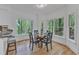 Dining area featuring a glass table, seating for four, and large windows offering views of the wooded property at 1913 Wild Dunes Dr, Raleigh, NC 27604