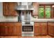 Close-up of oven and stovetop featuring stainless steel hood and wood cabinets at 201 Summergate Cir, Chapel Hill, NC 27516