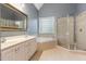 Bright bathroom features a double vanity, tub, and glass door shower at 216 Billingrath Turn Ln, Cary, NC 27519