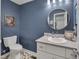 This bathroom boasts blue walls, a round mirror, and a neutral color palette for a modern aesthetic at 2442 Stevens Rd, Raleigh, NC 27610