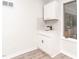This laundry area has white cabinetry, black hardware, a sink, and a window overlooking the porch at 2581 Green Valley Blvd, Burlington, NC 27217