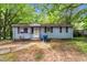 Charming single-story home with light blue siding and traditional shutters, nestled amongst mature trees at 2733 Thelma St, Durham, NC 27704