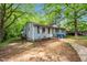 Exterior view of a light-blue one-story home surrounded by trees with a small front porch and walkway at 2733 Thelma St, Durham, NC 27704