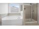 Bright bathroom featuring a large soaking tub and separate glass-enclosed shower at 311 Windrush Ln, Durham, NC 27703