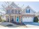Charming two-story home featuring stone accents, light-blue siding and a vibrant, eye-catching blue front door at 311 Windrush Ln, Durham, NC 27703