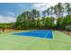 Enjoy a community tennis court with blue playing surface surrounded by green court and a mature tree line at 311 Windrush Ln, Durham, NC 27703