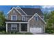 Charming two-story home with stone facade, gabled roof, and a welcoming front porch and attached two car garage at 3206 Armeria Dr, Apex, NC 27502