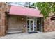 Brick building entrance with a red awning, glass doors, and bench seating at 3210 Environ Way, Chapel Hill, NC 27517