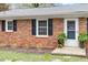 Close-up of a brick home's entrance featuring black shutters and landscaping at 3402 Pat Tilley Rd, Bahama, NC 27503