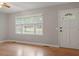 Living room with hardwood floors, a window with blinds, and a white front door at 3402 Pat Tilley Rd, Bahama, NC 27503