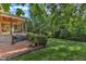 Charming backyard featuring a brick patio, covered porch, lush lawn, and well-manicured landscaping at 3824 Laurel Hills Rd, Raleigh, NC 27612