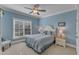 Comfortable bedroom with soft blue walls, a ceiling fan, and a large window offering natural light at 3824 Laurel Hills Rd, Raleigh, NC 27612