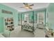 Stylish, mint-colored bedroom featuring a four-poster bed, ceiling fan, and abundant natural light through large windows at 3824 Laurel Hills Rd, Raleigh, NC 27612
