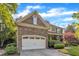Beautiful home exterior featuring a stone garage, brick accents, a well-manicured lawn, and lovely landscaping at 3824 Laurel Hills Rd, Raleigh, NC 27612