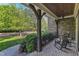 Cozy front porch with brick flooring, wooden support beams, decorative railings, and peaceful outdoor seating at 3824 Laurel Hills Rd, Raleigh, NC 27612