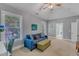 Bright living room with a comfortable blue sofa, ottoman, and a large window overlooking the landscaped yard at 3824 Laurel Hills Rd, Raleigh, NC 27612
