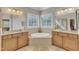 Bright bathroom featuring dual vanities, a soaking tub and large mirrors reflecting the bright light at 3824 Laurel Hills Rd, Raleigh, NC 27612