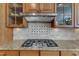 Close up of a gas range with stainless steel vent hood and granite countertops at 3824 Laurel Hills Rd, Raleigh, NC 27612