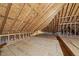 View of attic featuring exposed rafters, beams, plywood subfloor, and insulation ready for build out at 406 N Wakefield St, Zebulon, NC 27597
