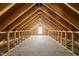 Unfinished attic space with exposed beams, plywood flooring, and a window for natural light ready to be finished at 406 N Wakefield St, Zebulon, NC 27597