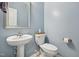 Charming half bathroom with pedestal sink, framed mirror, and soft blue walls at 409 Summit Trail Dr, Hillsborough, NC 27278