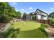 Beautiful backyard featuring a putting green, lush landscaping, and a modern home exterior at 4139 Rockingham Dr, Raleigh, NC 27609