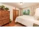 Bedroom with a four poster bed, hardwood floors, a wooden armoire, and windows with view of greenery at 449 Hill Rd, Franklinton, NC 27525