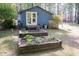 Landscaped backyard with a charming blue cottage featuring a garden, perfect for outdoor enjoyment at 449 Hill Rd, Franklinton, NC 27525