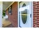 Close-up of the front door featuring a decorative glass insert, adjacent to a brick wall and a cozy porch with a white bench at 449 Hill Rd, Franklinton, NC 27525