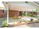 Covered brick patio with a dining table, porch swing, and manicured garden beds at 449 Hill Rd, Franklinton, NC 27525