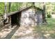 Rustic wooden storage shed in a wooded area with a dartboard and covered area to the side at 449 Hill Rd, Franklinton, NC 27525