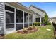 View of the home's screened-in porch and landscaped backyard featuring flowering bushes and healthy green grass at 450 Shale Creek Dr, Durham, NC 27703