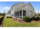 View of the home's screened-in porch and landscaped backyard featuring flowering bushes and healthy green grass at 450 Shale Creek Dr, Durham, NC 27703
