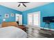Primary bedroom featuring bright blue walls, wood floors, access to a bathroom, and outdoor patio at 4793 Overhills Rd, Spring Lake, NC 28390