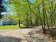 Scenic view of light blue home and long driveway, set within a lush, wooded landscape for privacy at 4793 Overhills Rd, Spring Lake, NC 28390