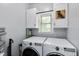 Bright laundry room with front loading washer and dryer, upper cabinets, and storage shelf at 4793 Overhills Rd, Spring Lake, NC 28390