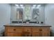 Bathroom with double vanity, framed mirrors, white trim, and window at 5632 Falkirk Dr, Durham, NC 27712