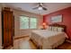 Bedroom with red accent wall, hardwood floors, ceiling fan, and large windows at 5632 Falkirk Dr, Durham, NC 27712