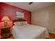 Bedroom with red accent wall, hardwood floors, and decorative headboard at 5632 Falkirk Dr, Durham, NC 27712