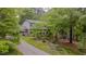 Exterior of home surrounded by mature trees, long driveway, and an American flag in the front yard at 5632 Falkirk Dr, Durham, NC 27712