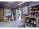 A cluttered garage with exposed wooden beams, shelving, and an open doorway at 5632 Falkirk Dr, Durham, NC 27712