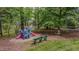 Backyard playground area featuring a colorful playset, bench seating, and mature trees at 5632 Falkirk Dr, Durham, NC 27712