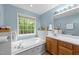 Relaxing bathroom featuring a jacuzzi-style tub, oak vanity, and bright natural light at 6204 Silver Spring Ct, Willow Springs, NC 27592