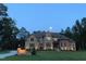 Beautiful home with stone and brickwork, complemented by manicured landscaping and nighttime lighting at 628 Carolina Crossings Dr, Apex, NC 27523