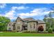 Stately stone and brick home with lush green lawn, manicured bushes and stone walkway at 628 Carolina Crossings Dr, Apex, NC 27523