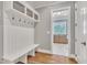 Mudroom with white bench seating, coat hooks, overhead storage, and hardwood flooring, and open doorway at 628 Carolina Crossings Dr, Apex, NC 27523